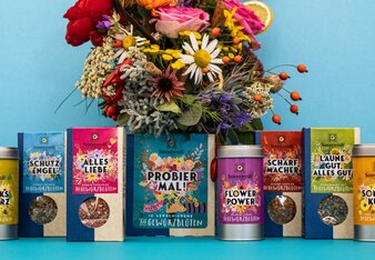 Auf dem Foto ist ein Blumenstrauß zu sehen. Vor dem Blumenstrauß stehen die Sonnentor Packungen Gewürzblüten. | © SONNENTOR