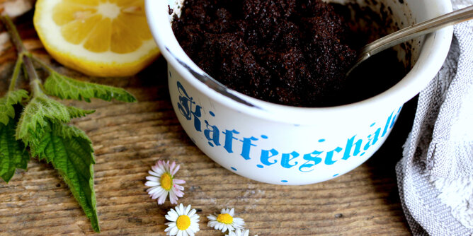 Koffein-Boost für's Haar | © SONNENTOR Auf dem Foto sieht man eine Schüssel mit einer Haarkur aus Kaffee darin. Daneben sieht man Gänseblümchen und eine Zitronenscheibe. | © SONNENTOR