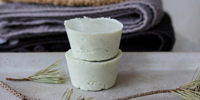 Dusch- Shampoobar | © SONNENTOR Auf dem Foto sind zwei Stück Shampoobars zu sehen. Im Hintergrund sieht man Handtücher. | © SONNENTOR