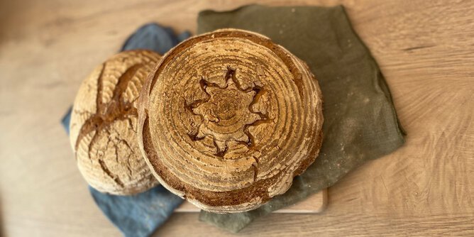 Brot gebacken | © SONNENTOR Auf dem Foto sieht man zwei gebackene Brotlaibe. In eines wurde ein Sonnenmuster eingestochen. | © SONNENTOR