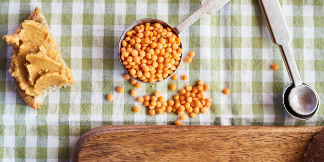 Kochen mit Hülsenfrüchte | © SONNENTOR Auf dem Foto ist eine Schaufel mit Hülsenfrüchten zu sehen. Daneben sieht man ein Brot mit Aufstrich. | © SONNENTOR