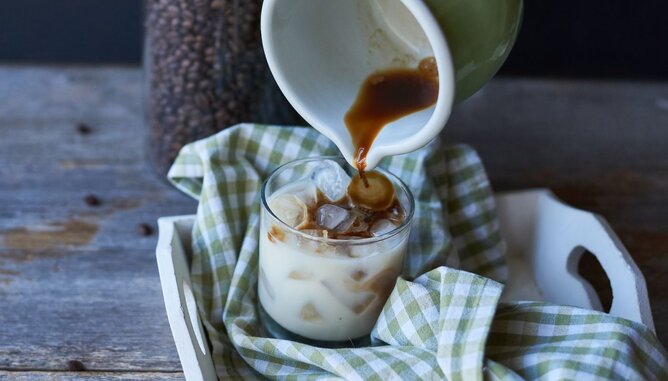 Nudelholz Kaffee Eiskaffee | © SONNENTOR Auf dem Foto sieht man wie Kaffee in ein Glas mit Eiswürfeln gegossen wird. | © SONNENTOR