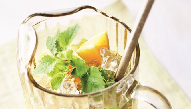 Cocktail | © SONNENTOR Auf dem Foto ist eine Karaffe mit Eistee Cocktail zu sehen. Darin sieht man eine Menge Eiswürfel, Minze und Zitornenstücke. | © SONNENTOR