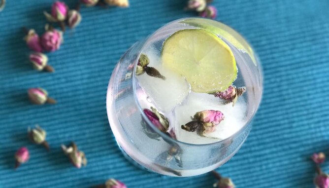 Eiswürfel | © SONNENTOR Auf dem Foto sieht man ein Glas mit Eiswürfeln darin. In den Eiswürfeln sind Rosenblütenknospen gefroren. | © SONNENTOR