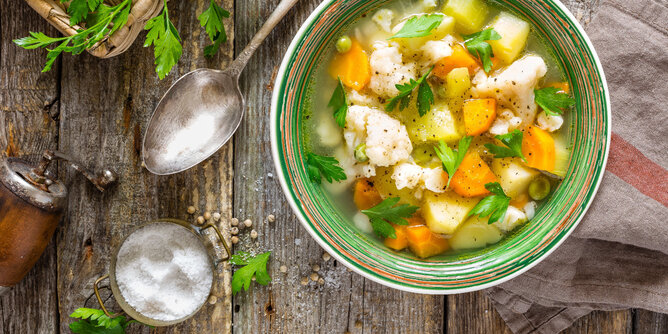 Basenfasten 2 | © SONNENTOR Auf dem Foto sieht man eine Schüssel mit Basenfasten Suppe. Daneben sind Gewürze und frische Petersilie zu sehen. | © SONNENTOR