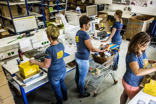 Auf dem Foto sieht man vier der Sonnentor Mitarbeiterinnen bei unterschiedlichen Verpackungstätigkeiten. | © SONNENTOR
